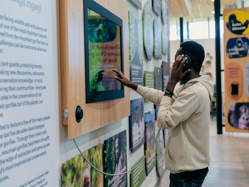 Visitor using headphones at wall-mounted screen